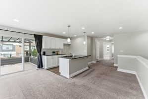 Open-concept living area with a kitchen island featuring a sink and pendant lighting