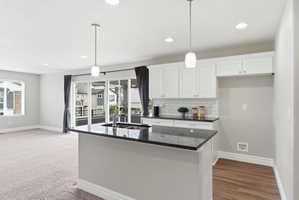 Modern kitchen island with dark countertop, white cabinetry, subway tile backsplash, and recessed lighting