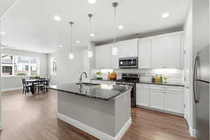 Kitchen featuring white shaker cabinetry, stainless steel appliances, dark stone countertops, and a subway tile backsplash