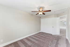 Carpeted room featuring a ceiling fan with integrated lighting, white baseboards, a built-in closet with bi-fold doors, and a paneled door