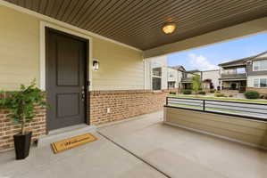 Front porch with concrete flooring and a dark panel door