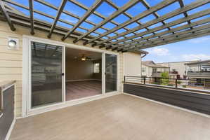 Spacious outdoor patio featuring a wooden pergola, concrete flooring, and an exterior wall lantern