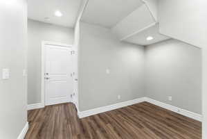 Interior space featuring wood-finish flooring, recessed lighting, and a white two-panel door with brushed nickel hardware