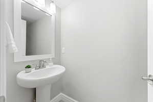 Pedestal sink with chrome faucet, framed mirror, and wall-mounted light fixture