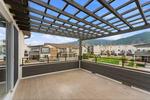Expansive exterior deck featuring a slatted pergola, composite decking, and dark horizontal siding