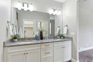 Double vanity with white cabinetry, granite countertop, and undermount sinks