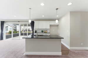 Kitchen island with a dark countertop and integrated sink, complemented by white upper cabinetry and a subway tile backsplash
