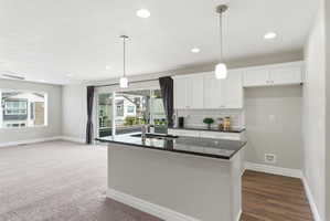 Kitchen island with a dark countertop and undermount sink, complemented by white cabinetry and a subway tile backsplash