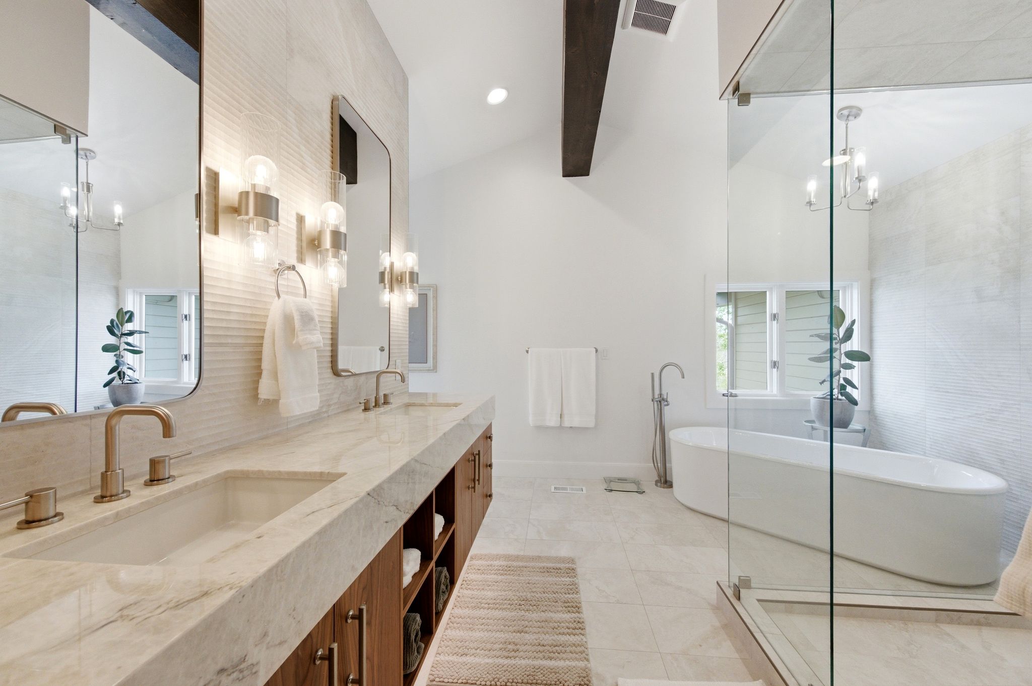 Bathroom featuring a freestanding soaking tub, an expansive glass-enclosed shower, and a dual vanity with integrated sinks
