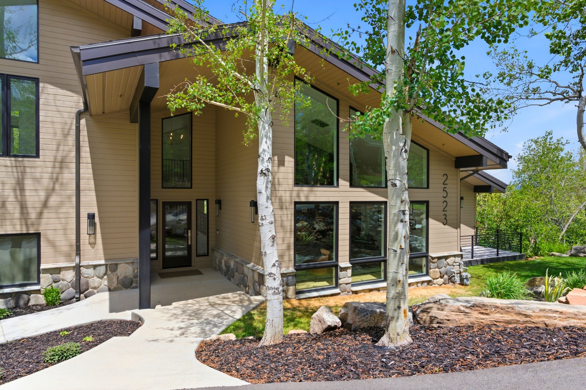 Contemporary exterior featuring tan siding and a natural stone foundation