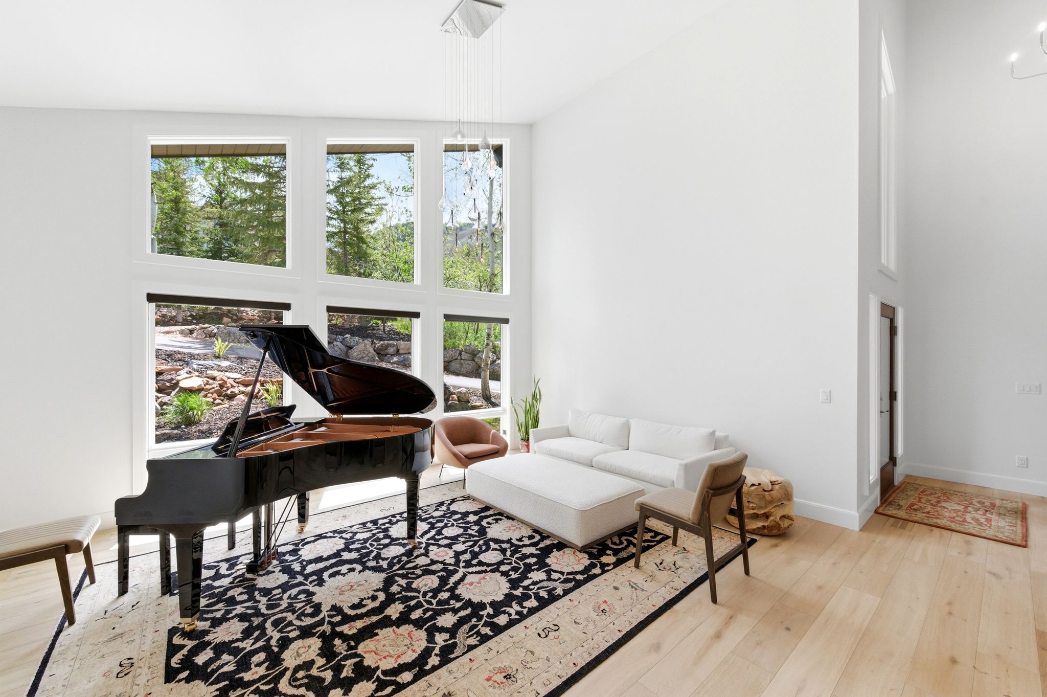 Spacious room with high ceilings, light wood-finish flooring, and expansive windows