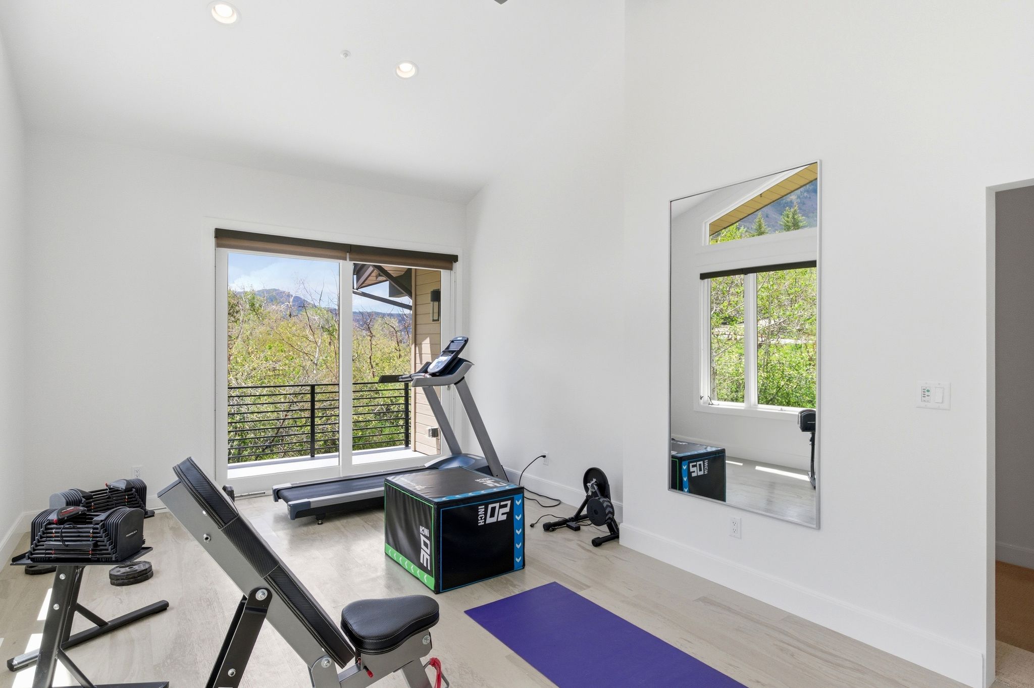 Spacious room with wood-finish flooring, recessed lighting, and a full-length wall mirror