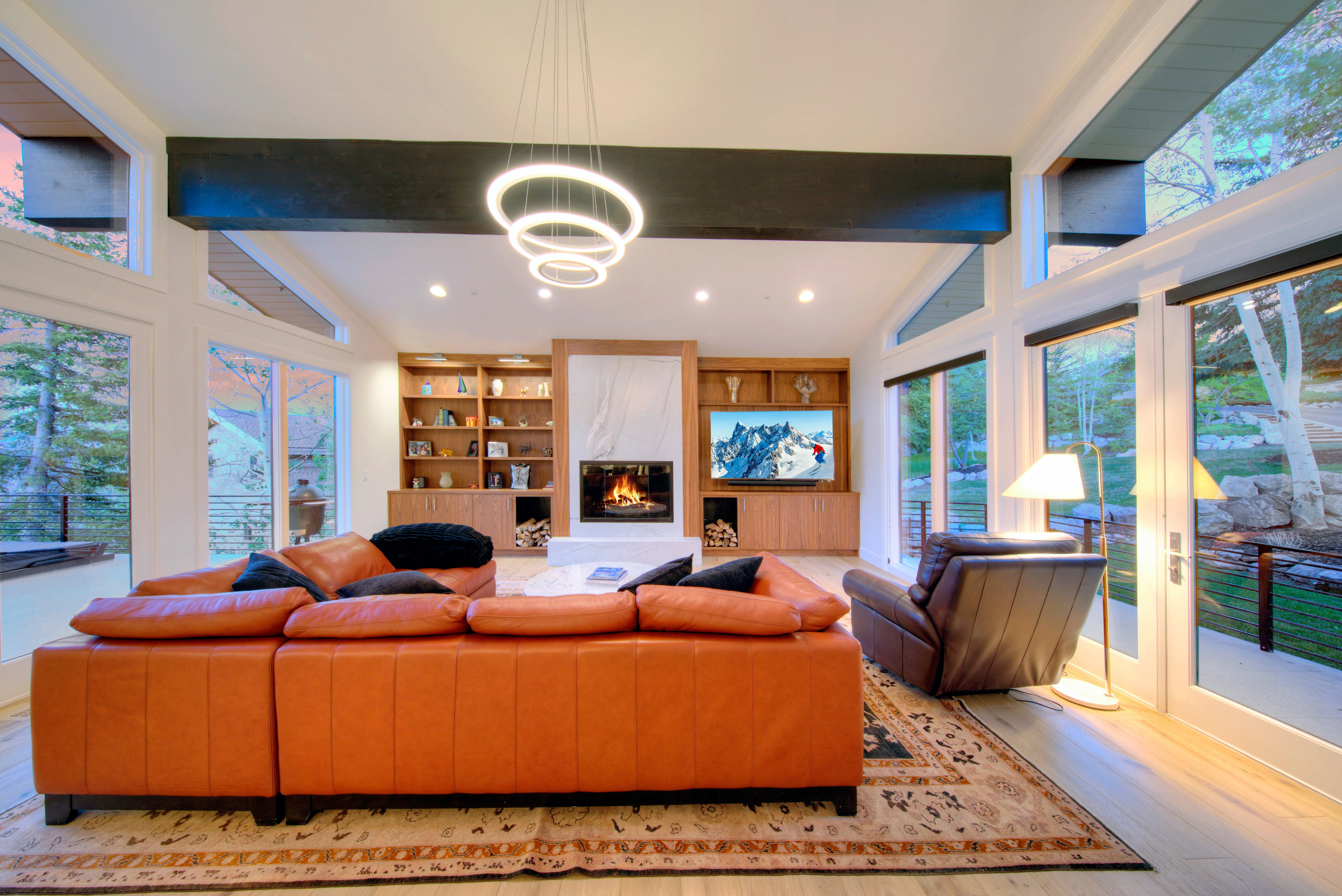 Spacious living area featuring high ceilings, a contemporary chandelier, and light wood-finish flooring
