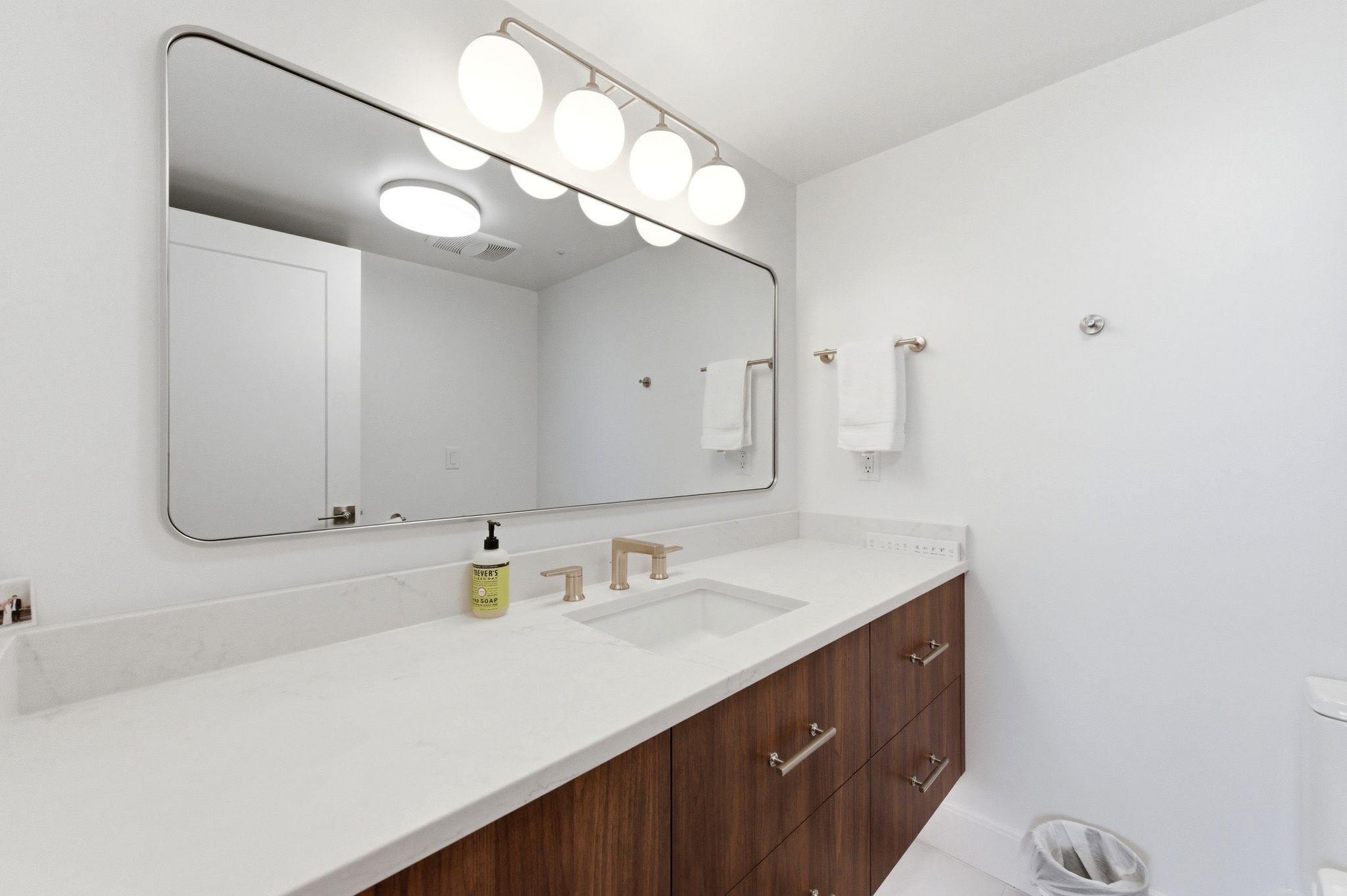 Contemporary bathroom vanity featuring a quartz countertop with an integrated rectangular sink