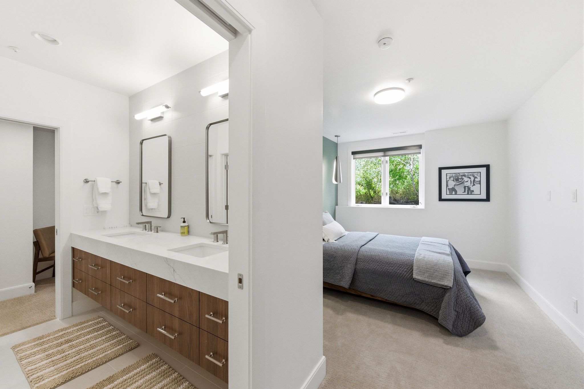 Dual vanity bathroom featuring a wood-finish floating cabinet with extensive storage, two rectangular sinks, and an expansive countertop