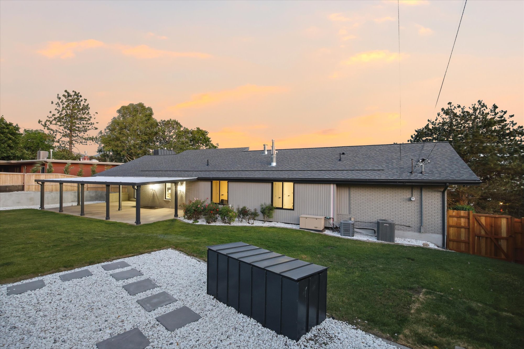 Expansive backyard featuring a covered patio, manicured lawn, and a decorative stone pathway