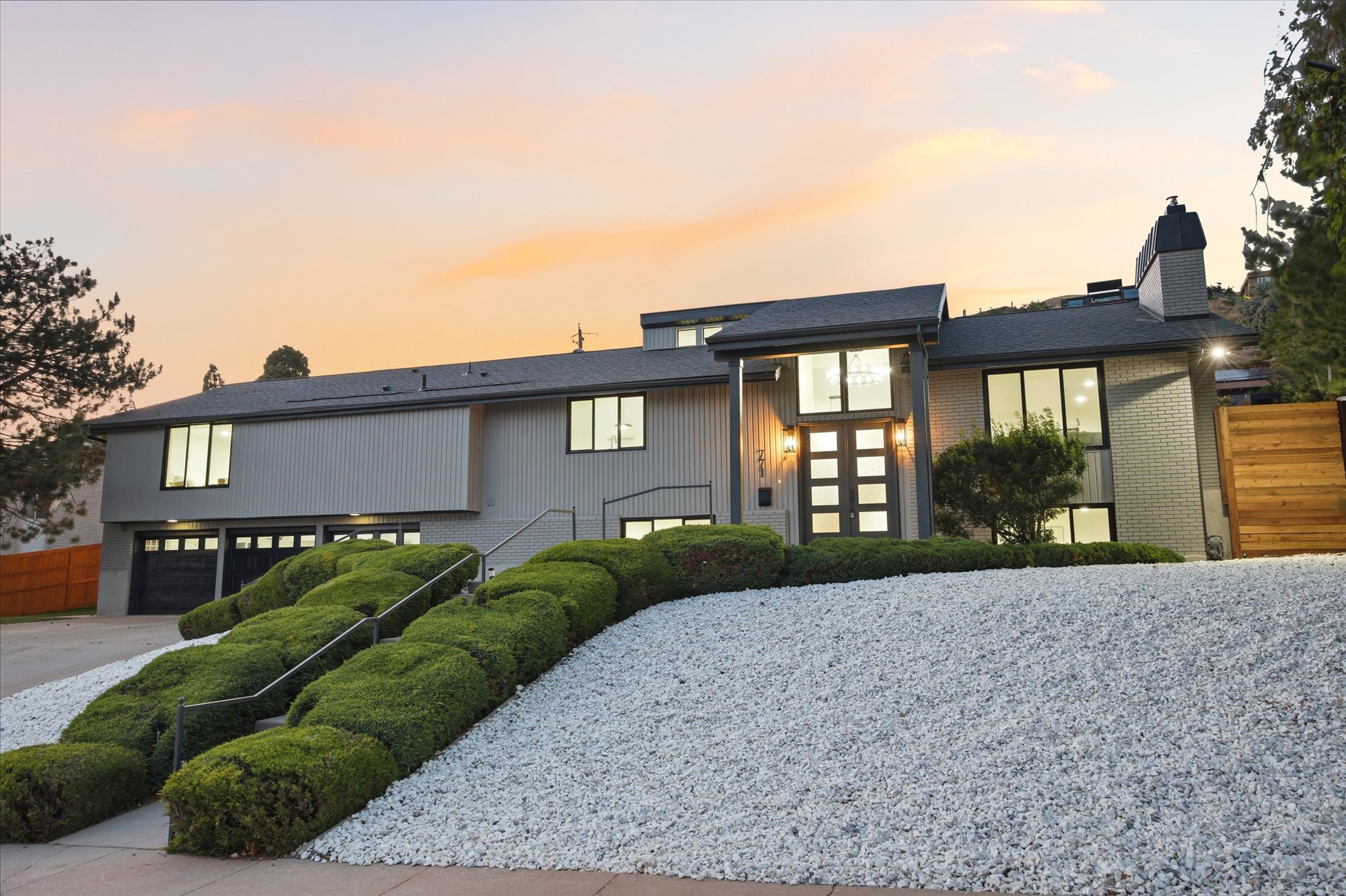 Modern architectural exterior featuring a prominent two-story entry, a split-level design, and a three-car garage