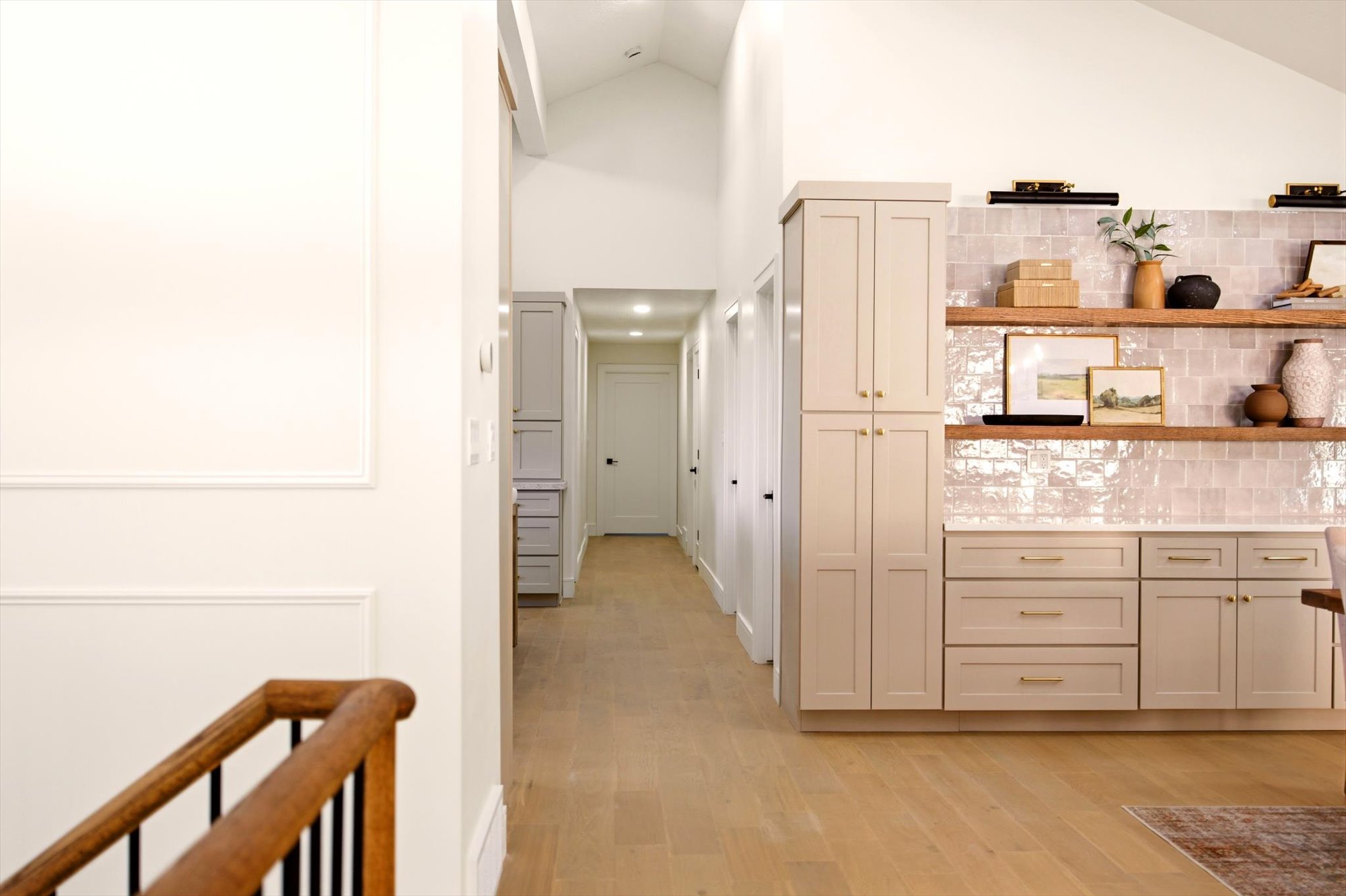 Open-concept interior featuring light wood-finish flooring, vaulted ceilings, and a built-in cabinetry unit
