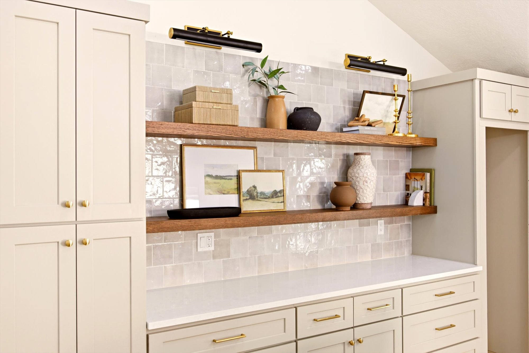 Built-in cabinetry with brass hardware, open wood-finish shelving, and a patterned tile backsplash