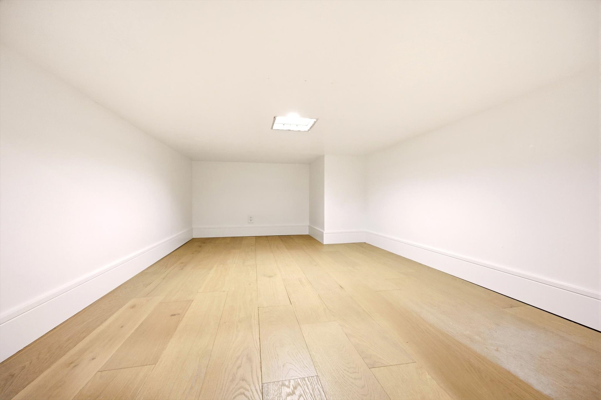 Bright room featuring wood-finish flooring, white walls, white baseboards, and a recessed ceiling light