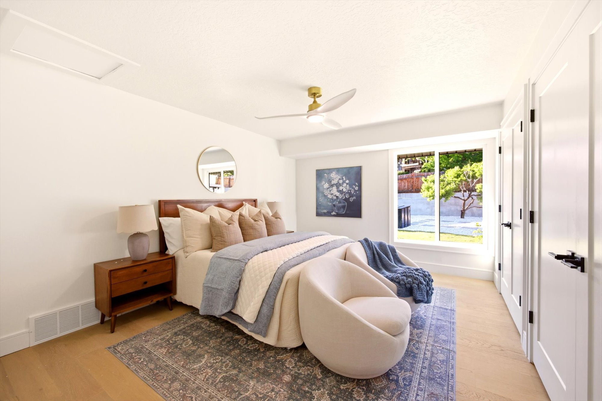 Spacious bedroom featuring light wood-finish flooring and a contemporary ceiling fan