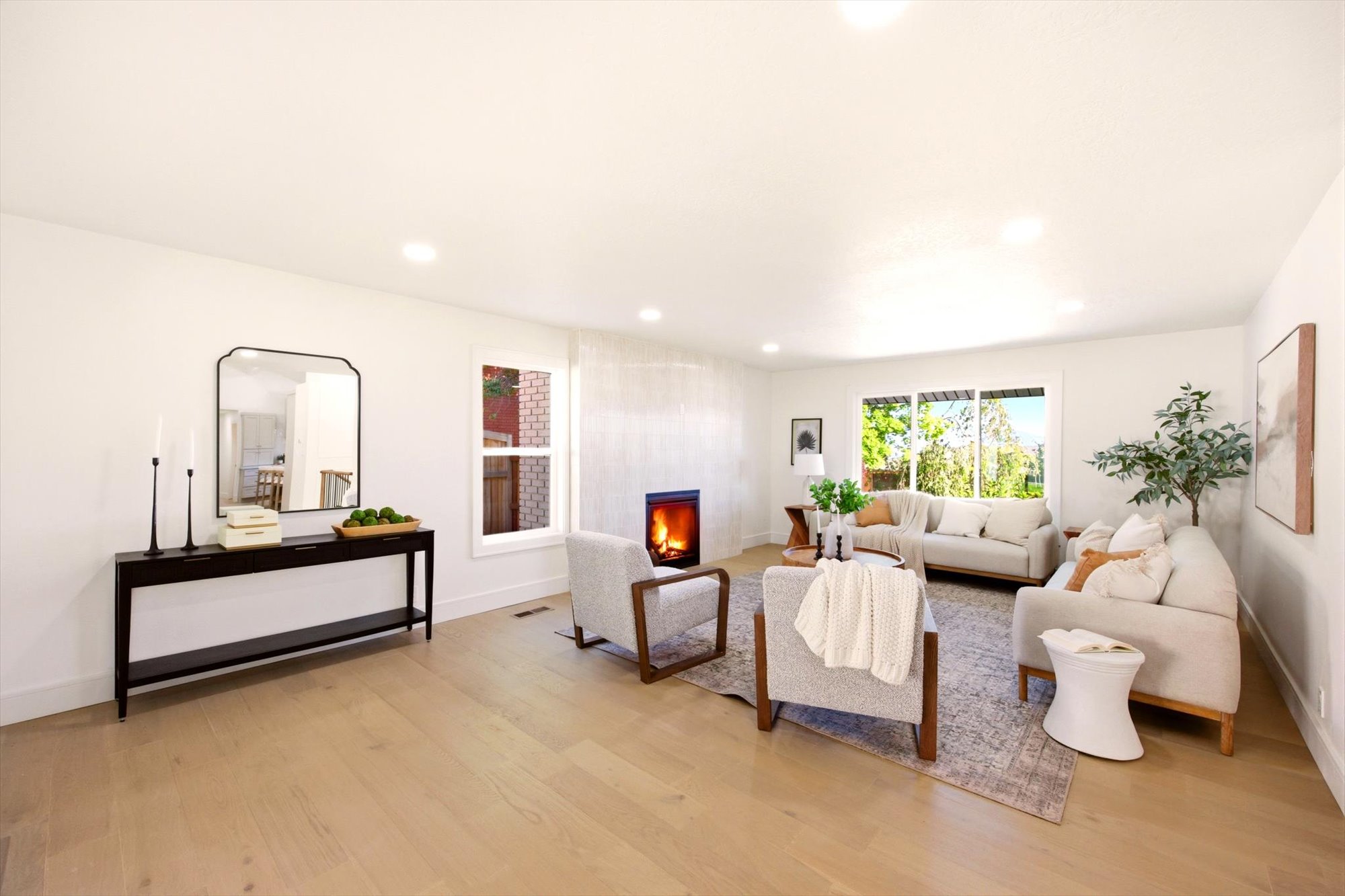Spacious living area featuring light wood-finish flooring, recessed lighting, expansive windows, and a built-in fireplace