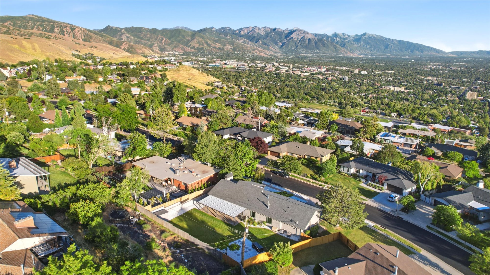 Expansive mountain backdrop with a residential area featuring numerous mature trees and varied architectural styles