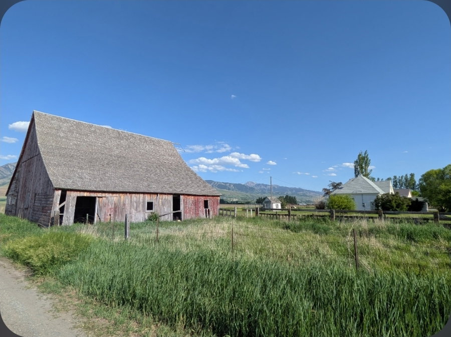 Red-sided barn with a gabled roof and open bays