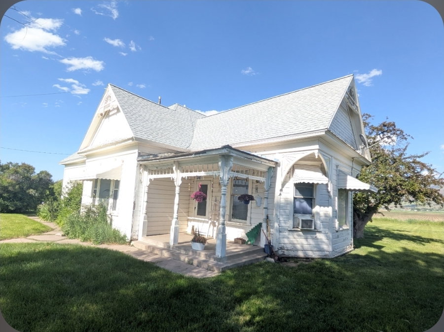 Victorian-style residence featuring a prominent front porch with decorative spindle work, a steeply pitched roof, and window awnings