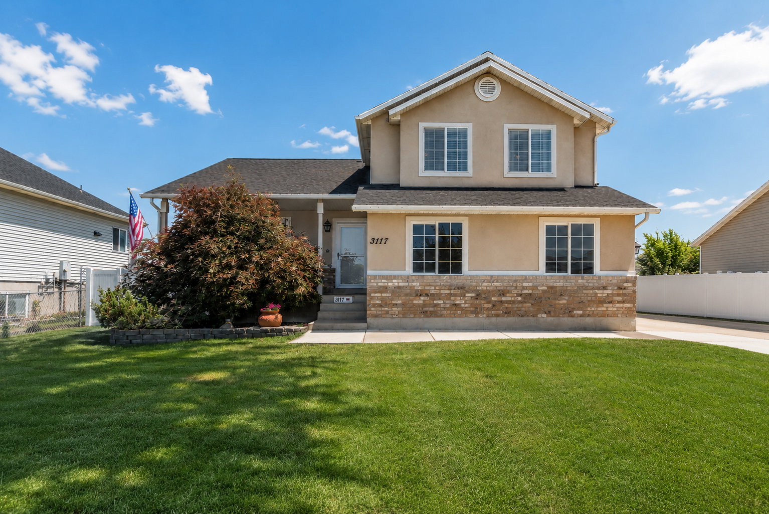Two-story stucco exterior with brick accent, gabled roof, and white window frames