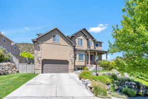 Multi-story residence featuring a two-car garage, stone accents, and a covered front porch