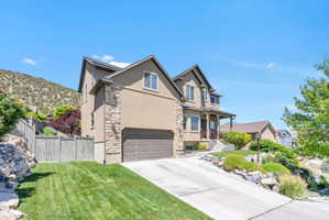 Two-story residence featuring stucco and stone veneer siding, an attached two-car garage, and a covered porch entry