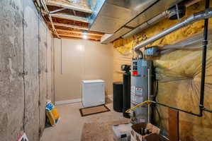 Utility area featuring a water heater, water softener, and exposed ceiling joists