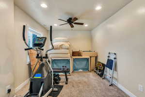 Recessed lighting illuminates this versatile room, featuring a textured carpet flooring and a ceiling fan