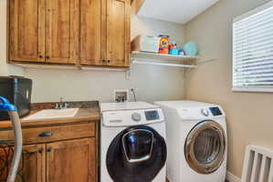 Dedicated laundry area featuring wood cabinetry, a utility sink, a spacious countertop, and an upper wall shelf