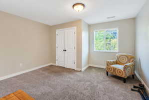 Spacious room featuring neutral-toned walls, plush carpet flooring, a double-door closet, and a window with horizontal blinds