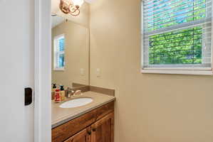 Vanity area featuring a wood-finish cabinet, integrated sink, and stone-look countertop