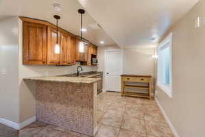 Kitchenette featuring wood cabinetry, granite countertops, and a tiled breakfast bar