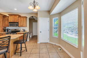 Kitchen featuring light wood cabinetry, stainless steel appliances, and an eat-at peninsula with granite-finish countertops