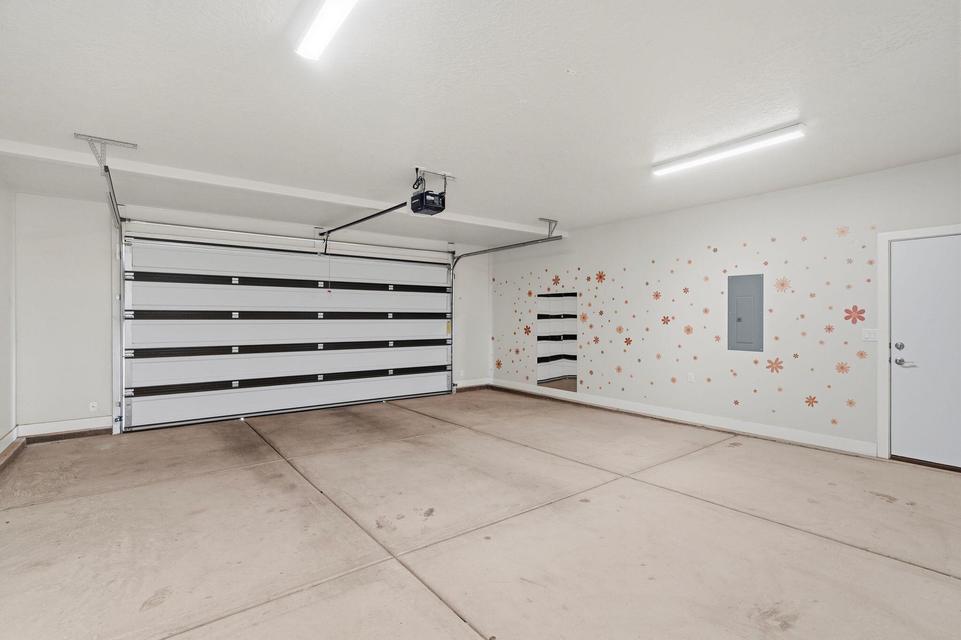 Spacious garage featuring a sectional overhead door with an automatic opener, concrete flooring, and built-in shelving