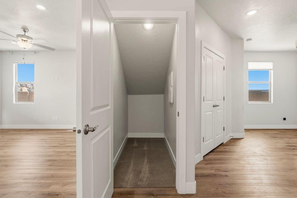 Hallway featuring wood-finish flooring, white walls, recessed lighting, and a closet with bifold doors