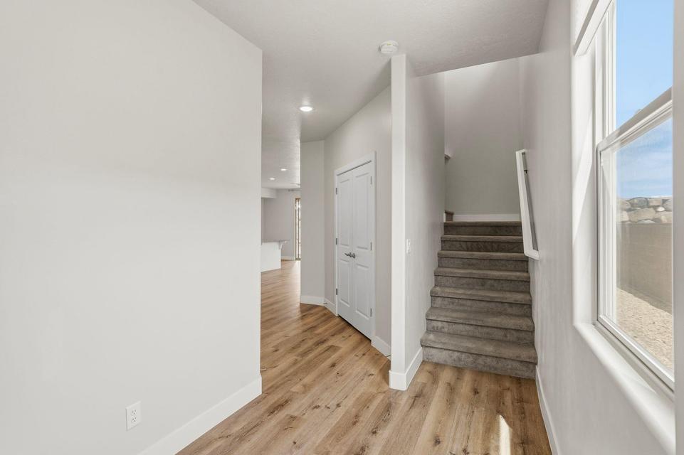 Entryway featuring wood-finish flooring, a carpeted staircase with a white handrail, a double-panel door, and recessed lighting