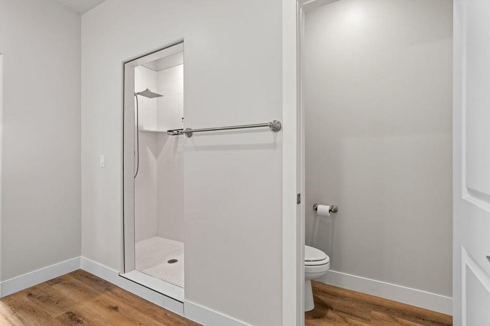 Walk-in shower with a glass enclosure, white tile surround, and a rainfall showerhead
