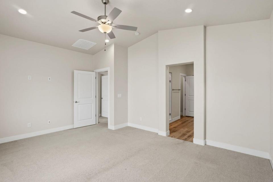 Spacious room featuring neutral carpeting, recessed lighting, a ceiling fan with light fixture, and white trim