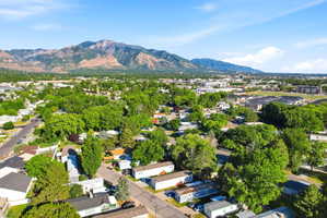 Expansive regional landscape featuring a distant mountain range, abundant mature trees, residential properties, and commercial structures