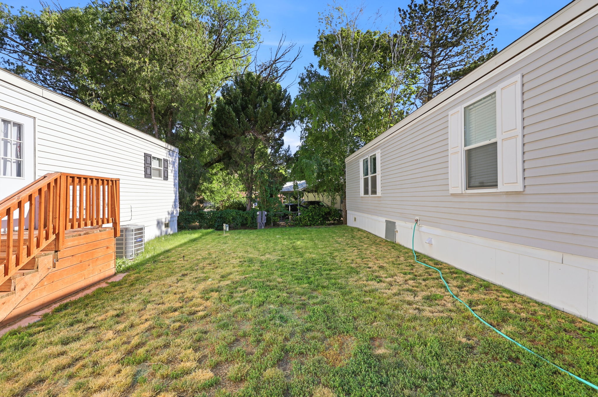 Expansive grassy yard area with mature trees and a wood deck