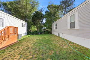 Expansive grassy yard area with mature trees and a wood deck