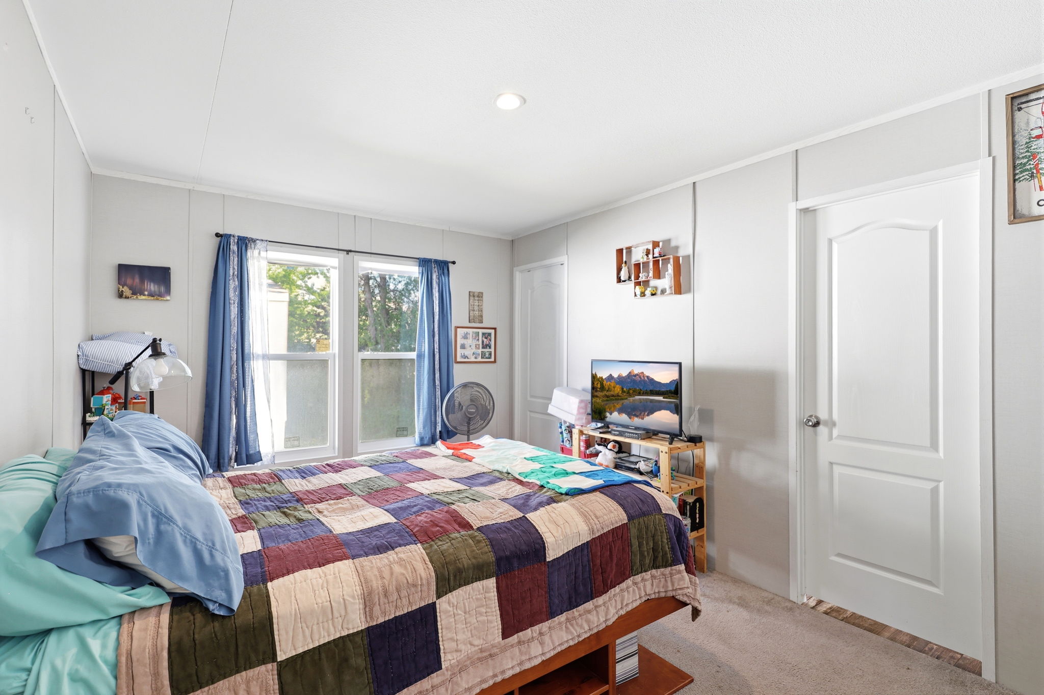 Bedroom featuring two windows with blue draperies, recessed ceiling lighting, light gray paneled walls, and carpet flooring