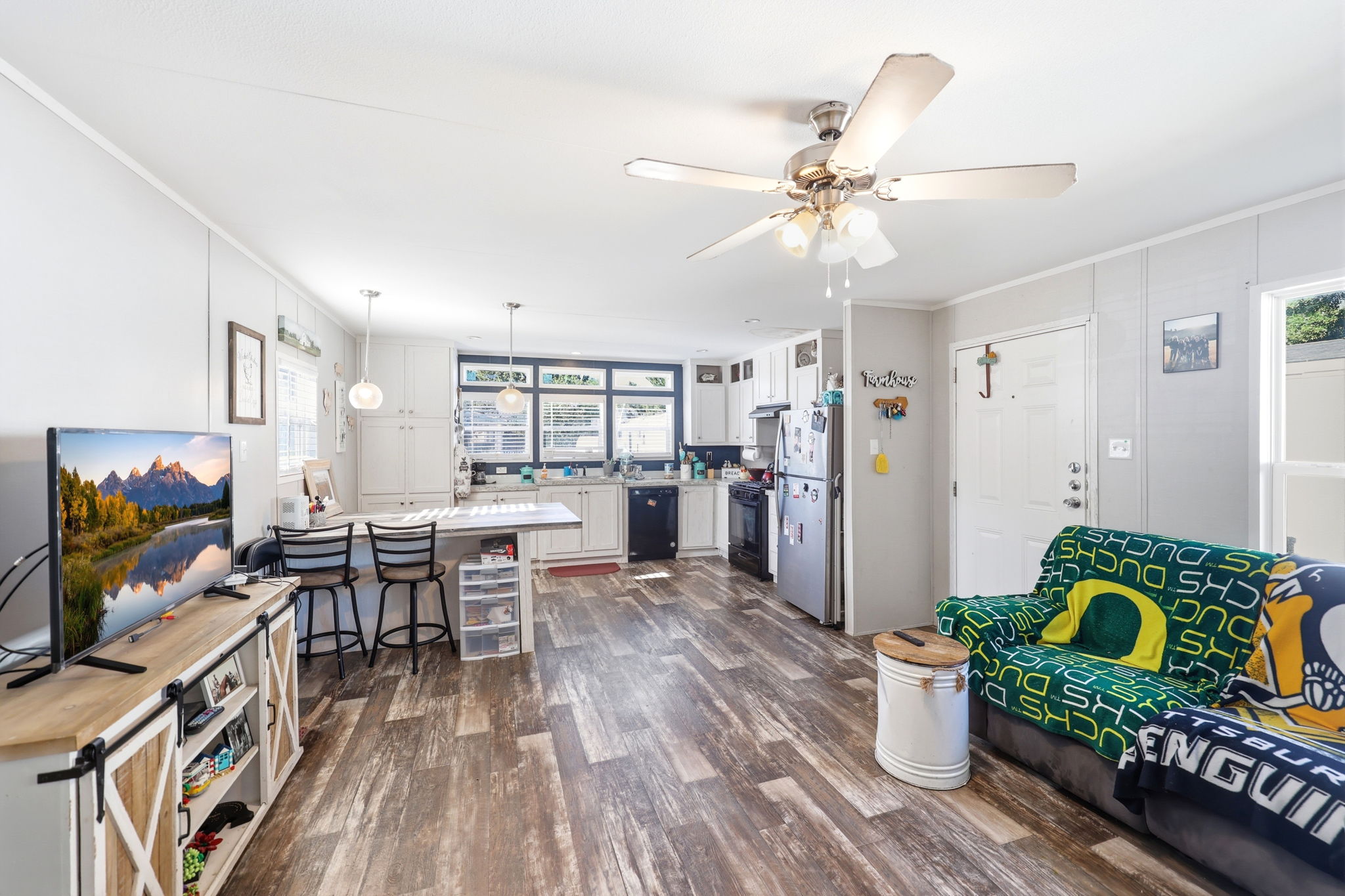 Spacious open-concept living area featuring wood-finish flooring and a ceiling fan