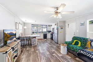 Spacious open-concept living area featuring wood-finish flooring and a ceiling fan